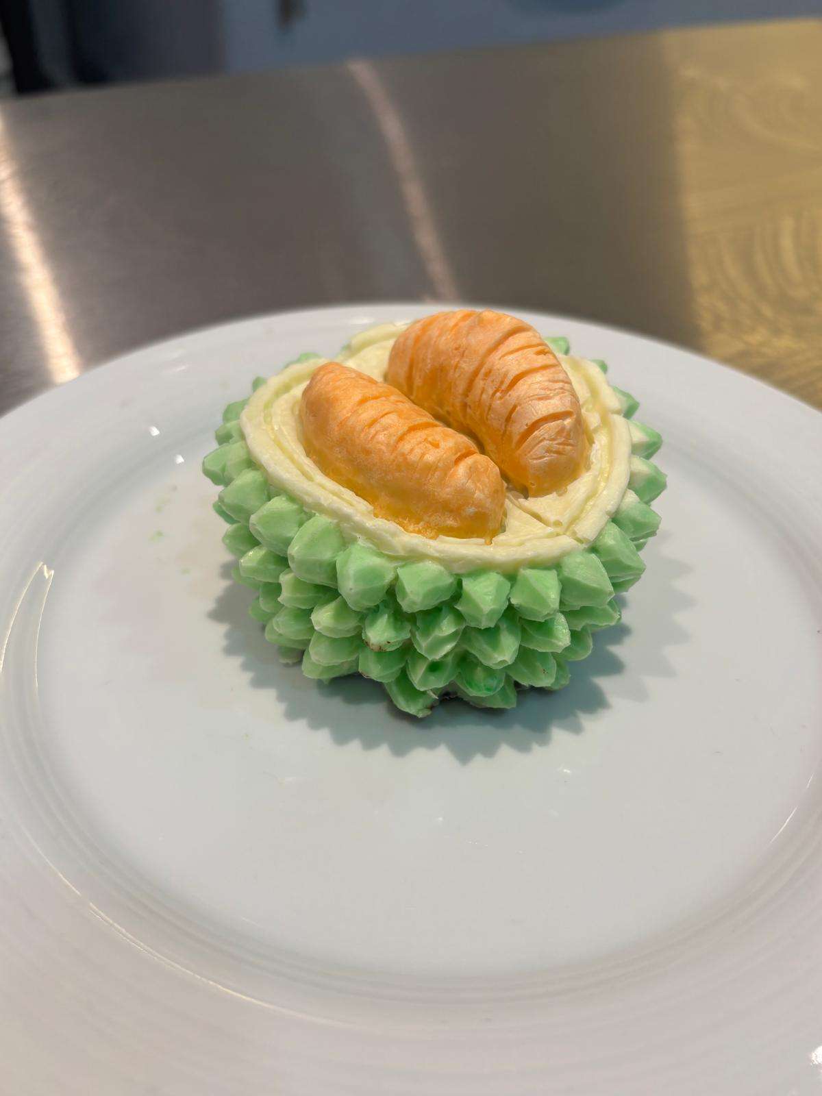Unique durian-shaped pastry with green frosting and small croissants on top.
