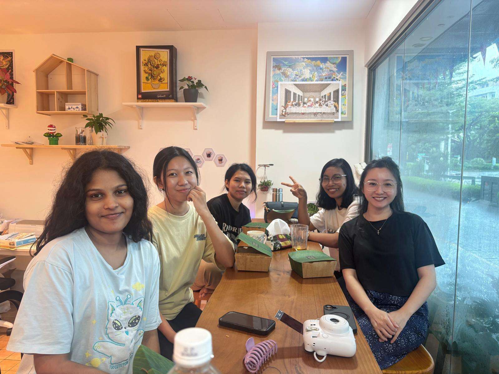 Group of friends smiling and posing with durian cakes at a dining table.